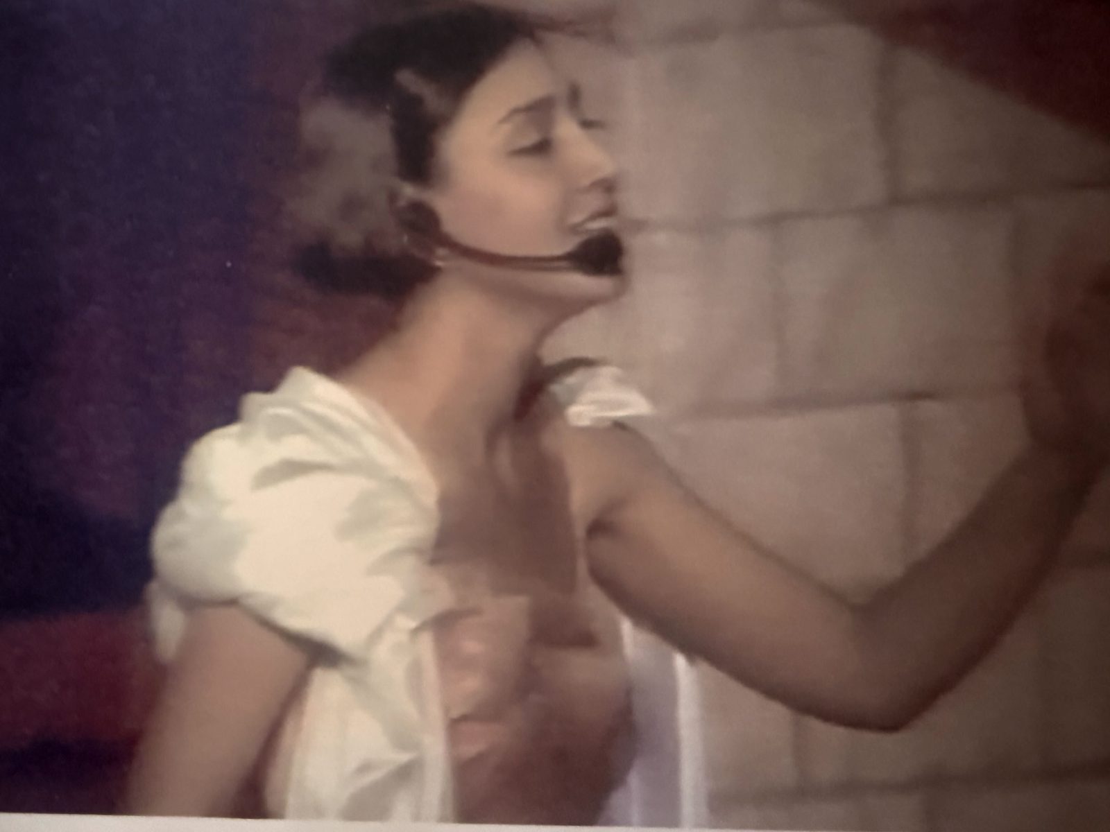 Angela performing on stage with a headset microphone during her professional theater career