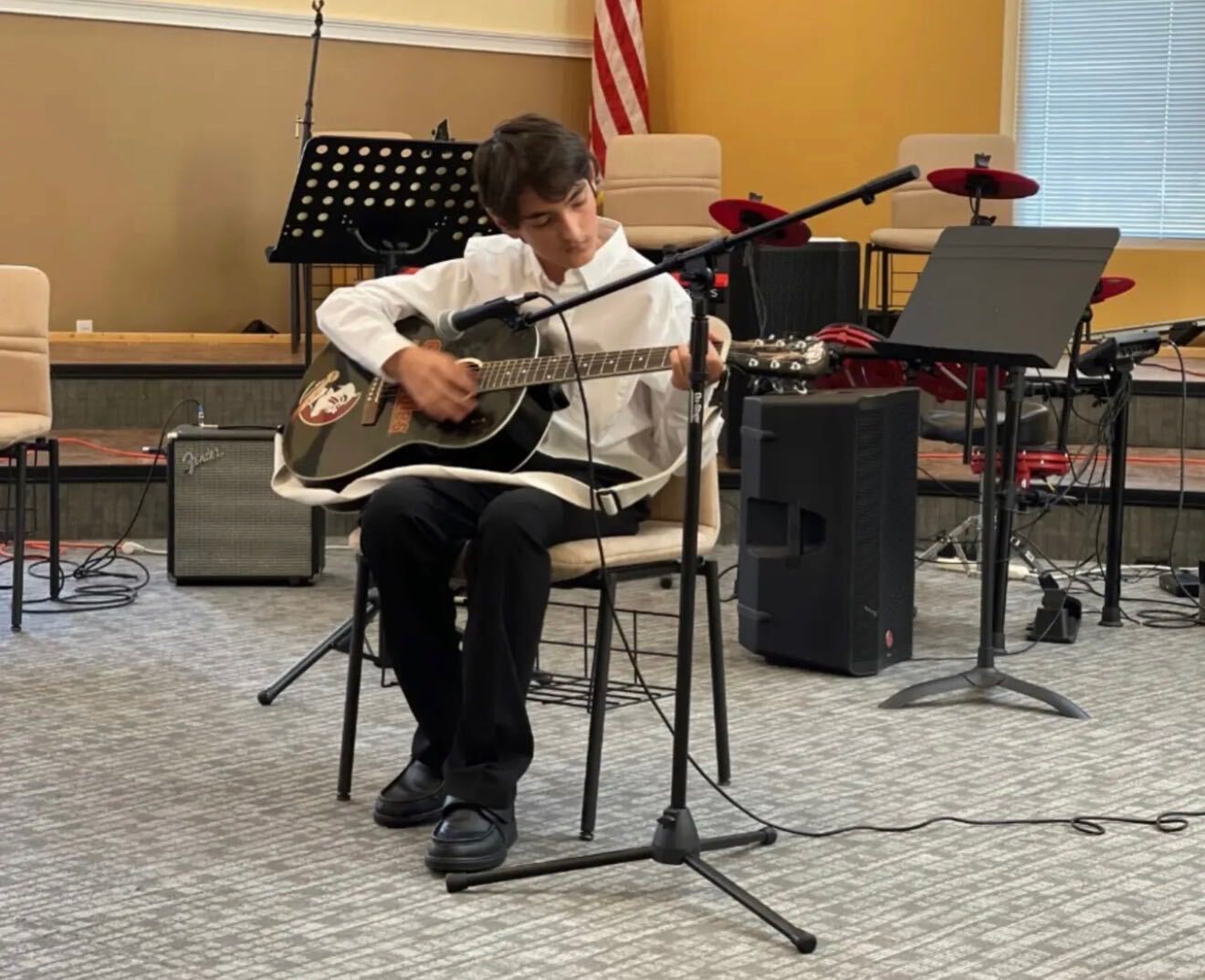 Student performing acoustic guitar at a recital