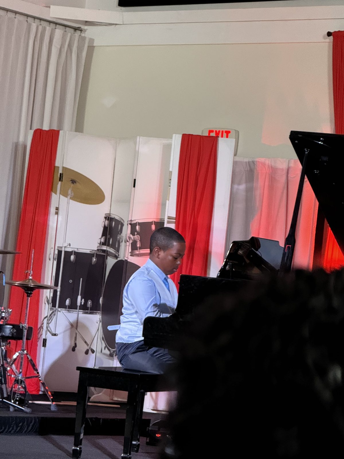 A student performing a piano recital on stage at Toguz Music and Performing Arts