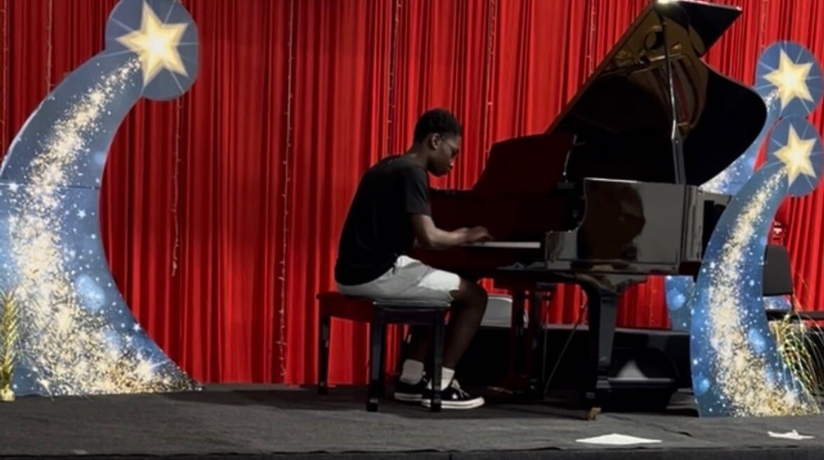Student performing a piano recital on stage